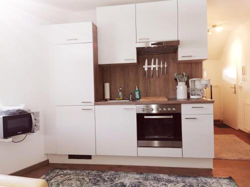 伊姆斯特Ferienwohnung Cooldog Kuschelnest的厨房配有白色橱柜和黑烤箱。