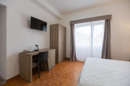 罗马Hotel Nova Domus Aurelia的一间卧室配有一张床和一张书桌及电视