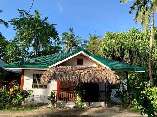 卢纳将军城Pore's Homestay的一座白色的小房子,设有绿色屋顶