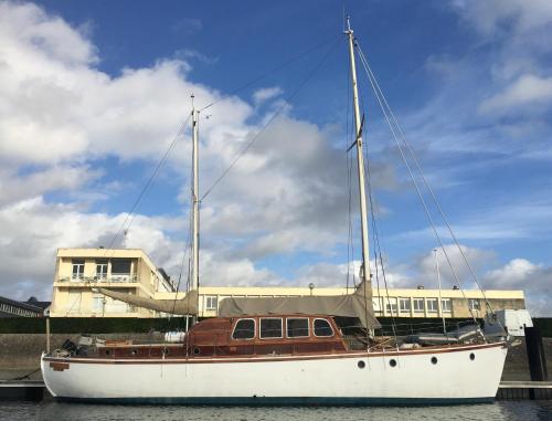 多维尔Port Deauville Yacht vintage的坐在建筑物前的水面上的船
