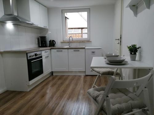 新明斯特Nordunterkunft的厨房配有白色橱柜和桌椅