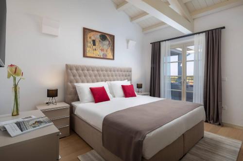 布罗托尼贾Villa Alicia by ILC (Istria Luxury Collection)的一间卧室配有一张带红色枕头的大床