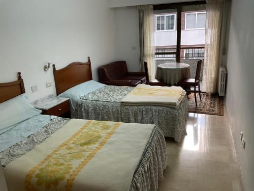 奥伦塞RESIDENCIA UNIVERSIDAD的客房设有两张床、一张桌子和一扇窗户。