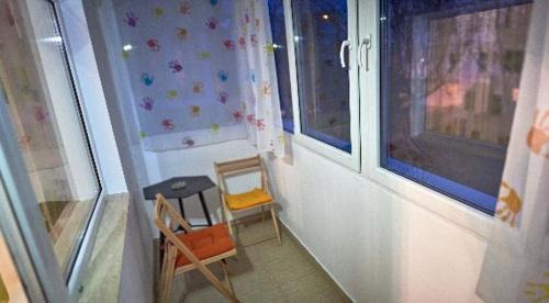 克卢日-纳波卡Apartament 2 camere cu loc de parcare的一间设有两把椅子、一张桌子和两个窗户的房间