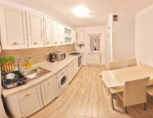 克卢日-纳波卡Apartament 2 camere cu loc de parcare的厨房配有白色橱柜、水槽和桌子
