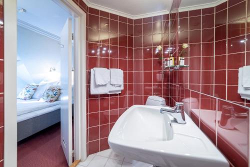桑内斯科隆恩戈德酒店的红色瓷砖浴室设有水槽和一张床