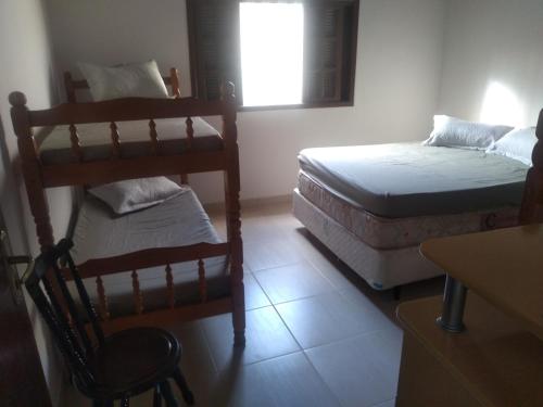 伯迪亚哥Casa de praia Indaiá Bertioga的客房设有两张床、一把椅子和窗户。