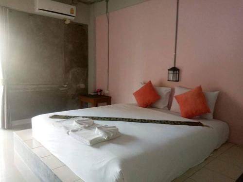 甲米镇The Guest Hotel Krabi的卧室配有带橙色枕头的白色床