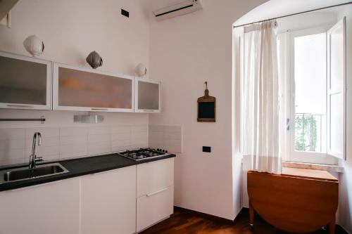 巴里CASA FISCARDI的厨房配有白色橱柜、水槽和窗户。