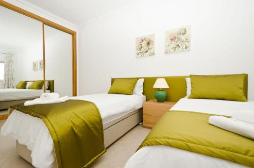 拉戈斯Fairviews Villa on Boavista Golf Resort的一间卧室配有两张带黄床单的床