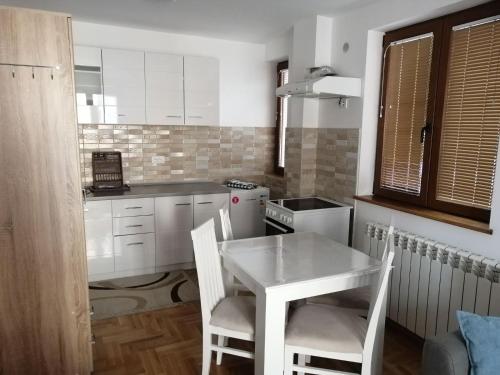 兹拉蒂博尔Vila Meridijan的小厨房配有白色的桌子和椅子
