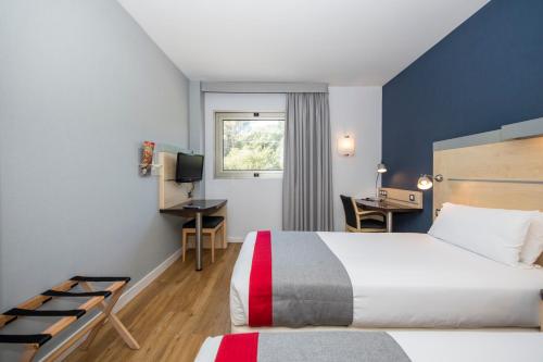 格拉诺列尔斯Holiday Inn Express Barcelona - Montmeló, an IHG Hotel的配有一张床和一张书桌的酒店客房