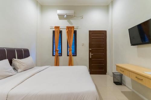 棉兰Vandolia Guest House Mitra RedDoorz的一间卧室配有一张床和一台平面电视