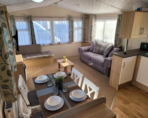 Great BillingLovely Static Caravan at Billing Aquadrome的厨房以及带桌椅的起居室。