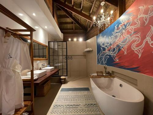 爱妮岛Mua Tala Hotel El Nido的一间带两个盥洗盆、浴缸和绘画的浴室