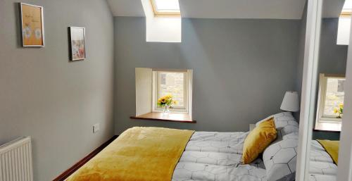 WistonThe Granary at Tinto Retreats, Biggar is a gorgeous 3 bedroom Stone cottage的一间卧室配有一张带黄毯的床和两个窗户