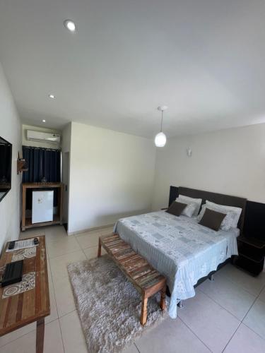 皮雷诺波利斯Pousada Yvanna的一间卧室配有一张床、一张长凳和一台电视。