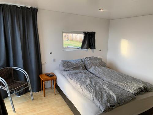 GufunesAdorable Tiny House in Reykjavik的卧室配有床、椅子和窗户。