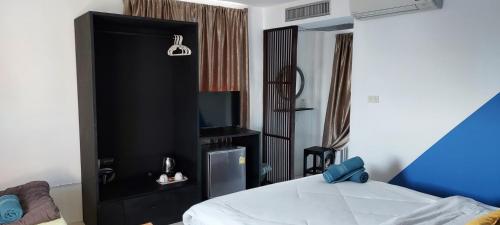 华欣Hua Hin Paradise Guesthouse的一间卧室配有一个黑色橱柜,配有电视
