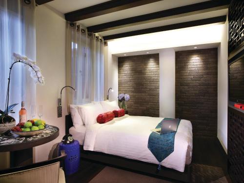 新加坡AMOY by Far East Hospitality的一间卧室配有一张床和一张带水果的桌子