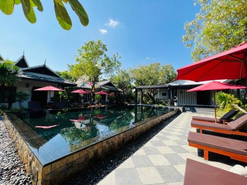 清迈Na Mantra Resort的一个带红伞的度假村的游泳池