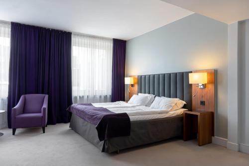 埃斯基尔斯蒂纳亿利达的一间卧室配有一张床和一张紫色椅子