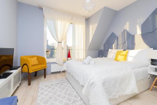 格但斯克Platinum Tartaczna Apartments by Renters的蓝色和白色的卧室,配有床和黄色椅子