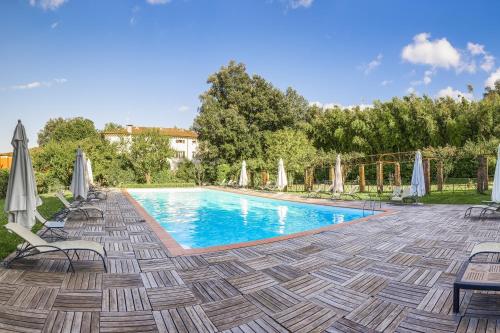 卢卡拉普林奇比萨别墅酒店的庭院内一个带椅子和遮阳伞的游泳池