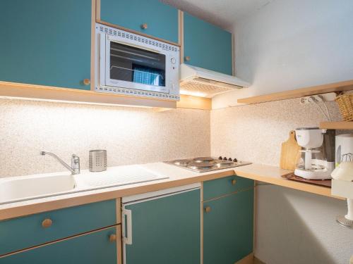 里蒙纽耶Apartment Le Jettay-13 by Interhome的一间小厨房,内配蓝色橱柜和微波炉