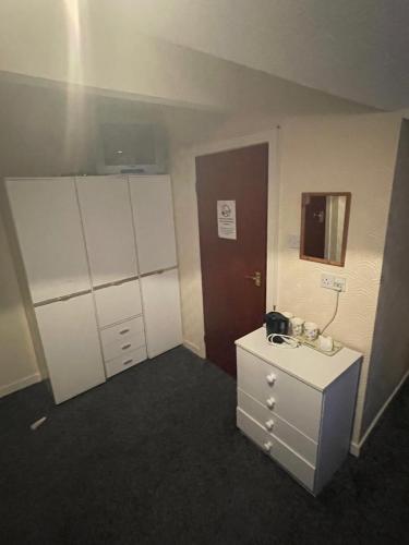 布莱克浦Highbury Hotel的一间设有白色橱柜和水槽的客房