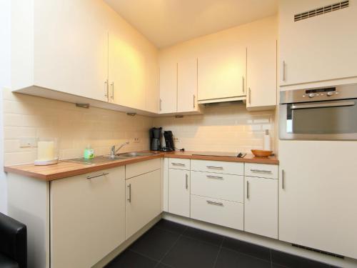 布列登Apartment Residentie Zeeparel by Interhome的厨房配有白色橱柜和不锈钢用具
