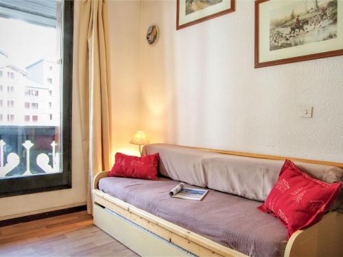 夏蒙尼-勃朗峰Studio Le Triolet-6 by Interhome的窗户客房内的一张带红色枕头的沙发