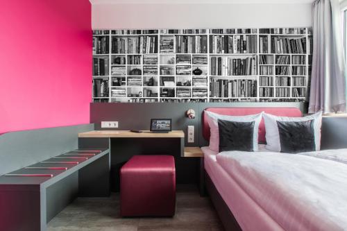 科隆SMARTY Cologne Dom Hotel - Boardinghouse - KONTAKTLOSER SELF CHECK-IN的一间卧室设有粉红色的墙壁、书桌和一张床