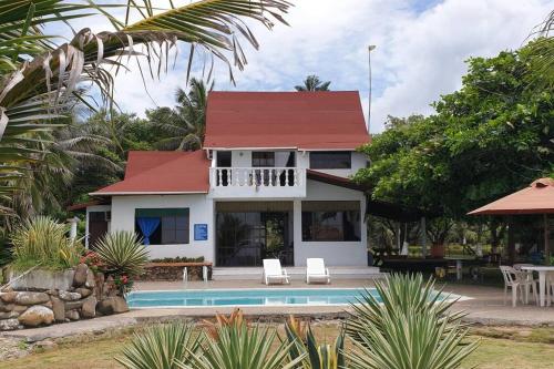 Puerto EscondidoCabaña PEDREGAL的白色的房子,有红色的屋顶和游泳池
