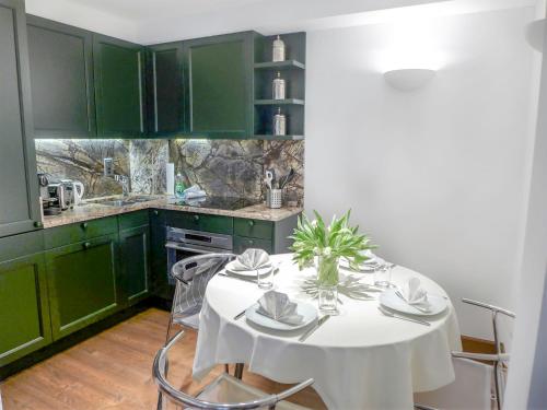 圣莫里茨Apartment Chesa Sonnalpine B 52 by Interhome的厨房配有绿色橱柜和白色桌椅