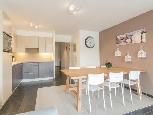 布列登Apartment Residentie Albatros by Interhome的厨房以及带木桌和白色椅子的用餐室。