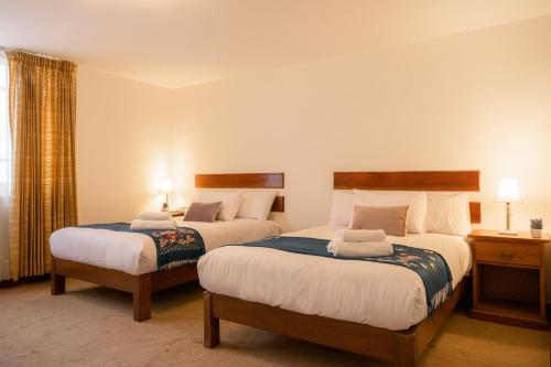 阿雷基帕Hotel Casa Campo by Cassana的酒店客房设有两张床和窗户。