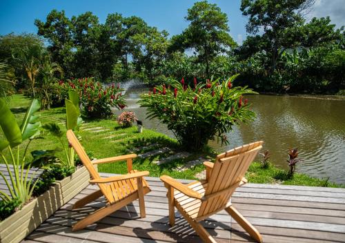 伯里塔卡Hotel La Finca Buritaca by DOT Premium的两把椅子坐在池塘旁的木甲板上