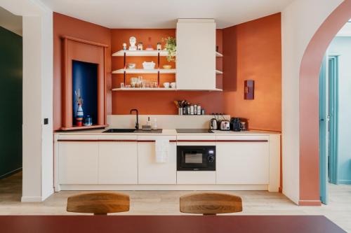 巴黎Edgar Suites Auteuil - Le Marois的厨房配有白色橱柜和橙色墙壁