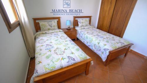 米迪克Marina Beach Appart Hôtel的一间卧室设有两张床和一个阅读卡马库拉海滩保险的标志。