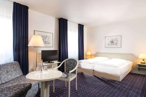梅特曼杜塞尔多夫梅特曼温德姆花园酒店的酒店客房配有床、沙发和桌子。