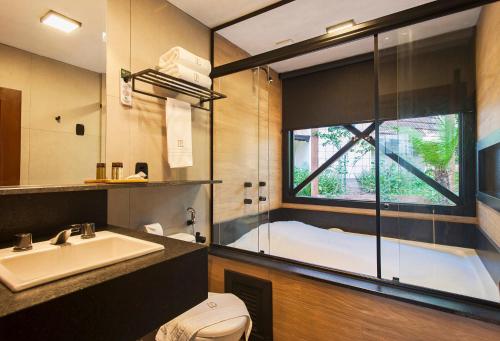 格拉玛多Hotel Fioreze Chalés的带浴缸、水槽和窗户的浴室