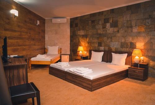 TamarinoХотелски Комплекс Копитото的一间卧室设有两张床、一台电视和两盏灯。