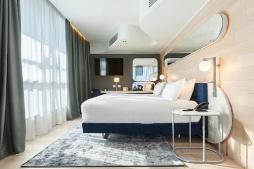 米兰voco Milan-Fiere, an IHG Hotel的酒店客房设有一张大床和一张桌子。