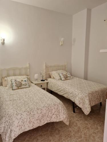 拉拉古纳Apartamento La Barranquera的白色墙壁客房的两张床