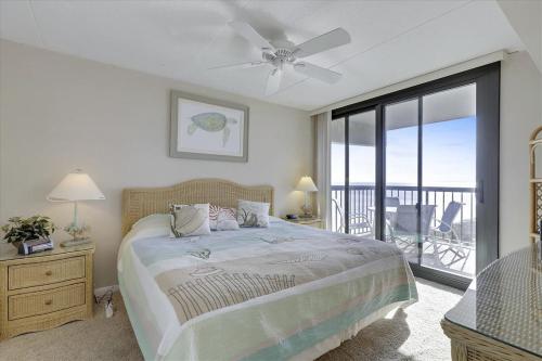 大洋城Sea Watch VII的一间卧室配有一张带吊扇的床和一个阳台