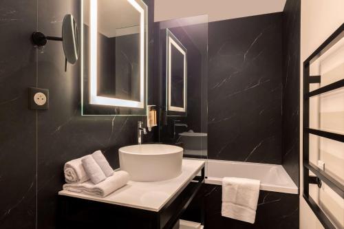 博瓦纪尧姆Best Western Plus Le Conquerant Rouen Nord的黑色浴室设有水槽和浴缸。