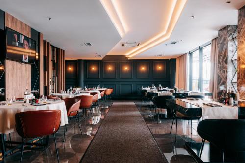 米特罗维察Palace Hotel & SPA的一间在房间内配有桌椅的餐厅