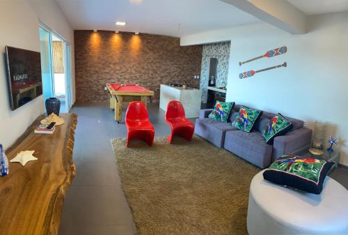 贝贝里比Tabubinha Paradise的客厅配有沙发和2把红色椅子
