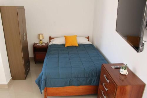 钦博特Departamento en Chimbote con cochera的一间卧室配有一张带蓝色棉被和黄色枕头的床